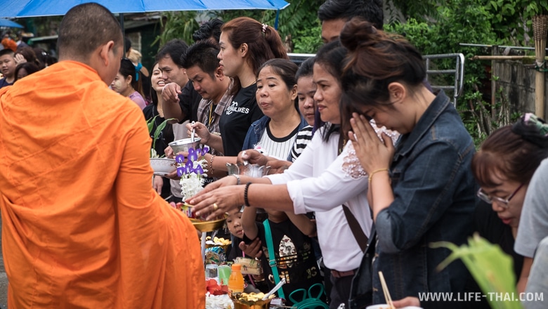 Люди отдают подаяние монаху и молятся, Таиланд