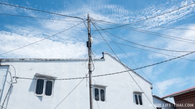 Белый дом на фоне синего неба и паутина из проводов