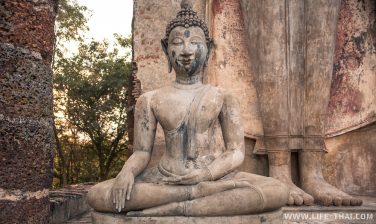 У ног огромного Стоячего Будды сидит ещё одна статуя