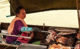 Женщина готовит морепродукты на грилле в лодке Что попробовать на плавучем рынке в Ампхаве