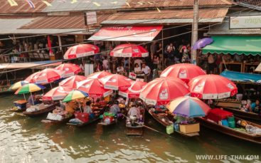 Лодки с красными зонтами на плавучем рынке Ампхава в Бангкоке