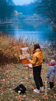 Девочка рисует пейзаж на берегу озера